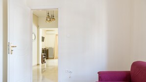 Ein Zimmer mit einem roten Sofa, einer weißen Tür und einem Flur, der in einen Küchenbereich führt.