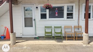 A porch with a wooden railing, a white door, and a window with blinds. There are three chairs and a broom on the porch. - 2 bedrooms with a shared pool. apt4 (Hampton)