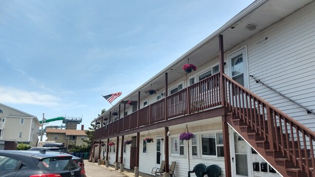 A motel with a two-story balcony, a flag, and hanging flower baskets. - 2 bedrooms with a shared pool. apt4 (Hampton)