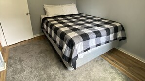 A bedroom with a bed, grey carpet, a white door, and a wall with a framed picture. - 2 bedrooms with a shared pool. apt4 (Hampton)