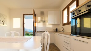 Een moderne keuken met witte kasten, een fornuis en een uitzicht door een open deur.