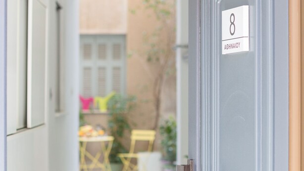 A hallway leading to a door with the number 8 and name "AOHNAOY" on it. - Grandma's Chic & Bright Athenian Home with a Patio (Athens)