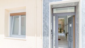 A modern entrance with a glass door and a window with a wooden blind. - Grandma's Chic & Bright Athenian Home with a Patio (Athens)