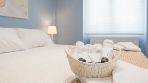 A neatly made bed with a basket of toiletries on the side. - Grandma's Chic & Bright Athenian Home with a Patio (Athens)