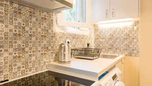 A kitchen with patterned tiles, a kettle, a dish rack, a washing machine, and a window. - Grandma's Chic & Bright Athenian Home with a Patio (Athens)
