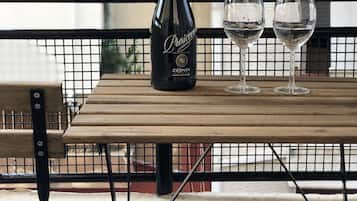 En flaska Prosaccio-vin och två glas på ett träbord, med ett metallräcke i bakgrunden.