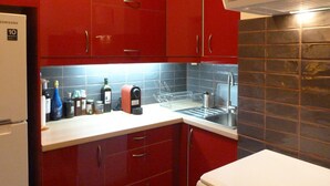 Una cocina pequeña con armarios rojos, una encimera blanca y un fregadero de acero inoxidable.