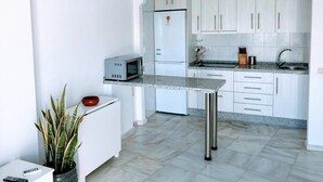 Een moderne keuken met witte kasten, een ingebouwde magnetron, een koelkast en een granieten aanrecht.