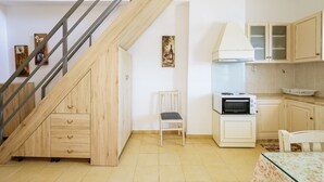 A kitchen with a built-in microwave, a chair, and a dining table.