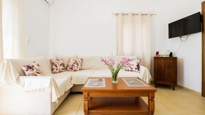 A living room with a sofa, a coffee table, a TV mounted on the wall, and a cabinet.