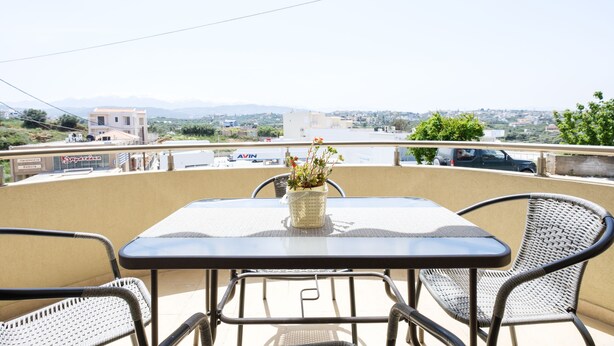 A balcony with a table and chairs, a potted plant, and a view of a cityscape.