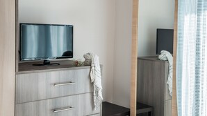 Ett modernt badrum med ett handfat i trä, en platt-TV och en spegel.