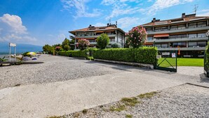 A residential area with two multi-story buildings, a gravel driveway, and a private entrance gate. - Sogno del Lago: in front lane of the beach in Manerba del garda (Manerba del Garda)