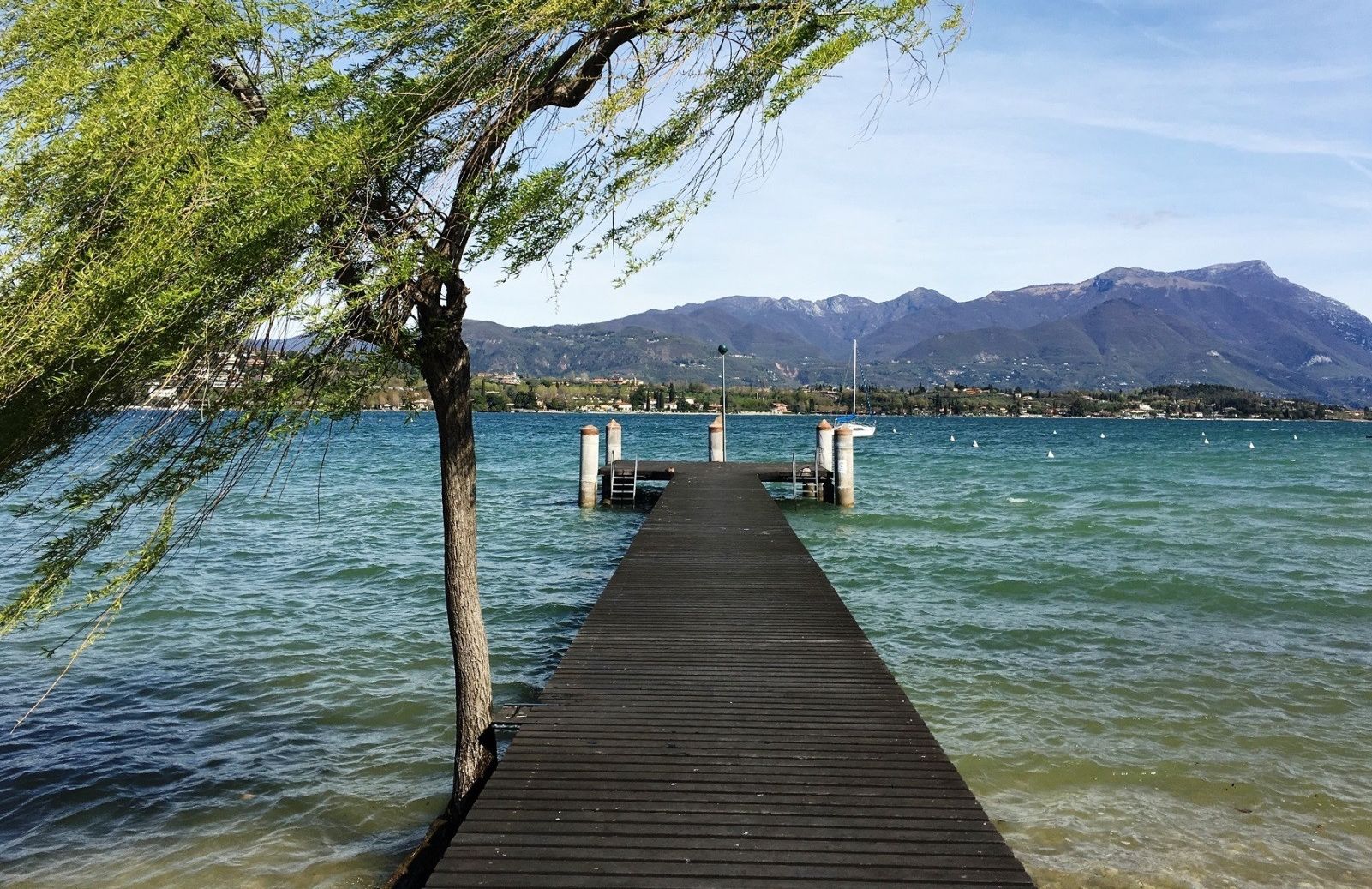 A wooden pier extending into a lake with mountains in the background.