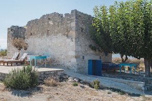 A stone building with a blue door, outdoor seating, and a tree.