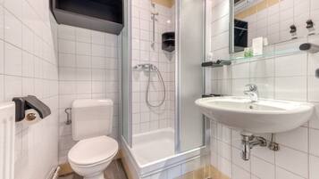 A modern bathroom with a toilet, a glass-enclosed shower, and a sink with a mirror above it.