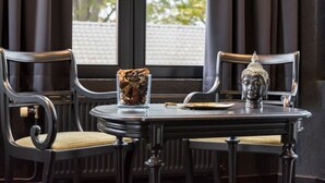 A table with a Buddha statue and a glass of dried flowers. - Hotel Mosa (Oupeye)