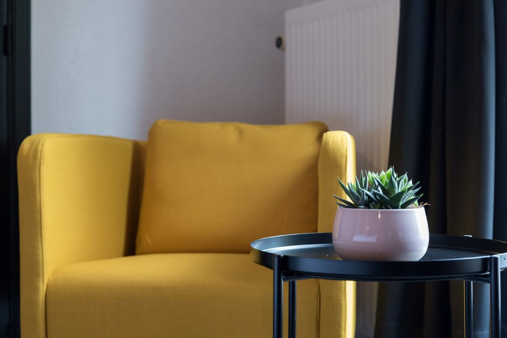 A yellow armchair and a small round table with a potted plant.