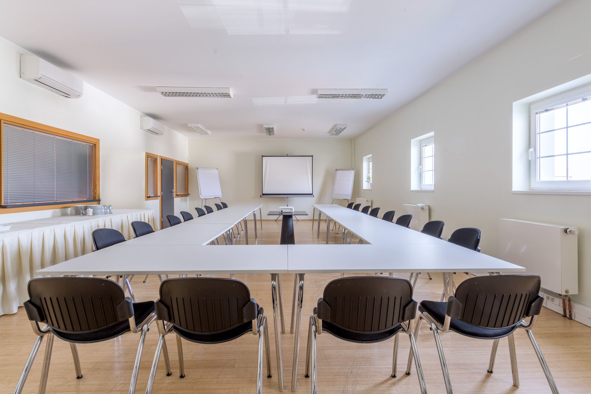 Une salle de conférence équipée d’une longue table, de chaises, d’un écran de projection et d’un tableau blanc.