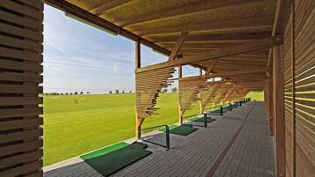 A covered seating area with a view of a grassy field.