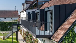 Une maison moderne dotée d’un balcon, d’un escalier et d’un jardin.