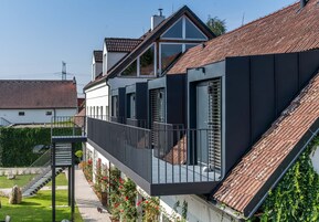 Una casa moderna con balcón, escalera y jardín.
