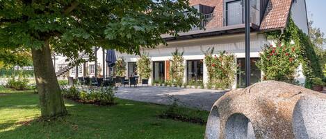 A modern building with a sloped roof, outdoor seating area, and a stone bench.