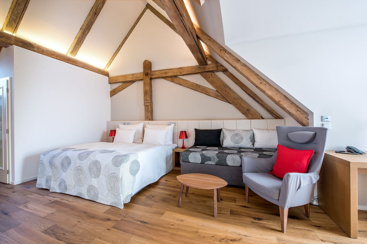 A bedroom with a bed, a sofa, a chair, and a desk.