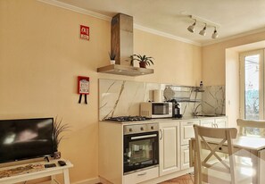 Une cuisine compacte équipée d’une cuisinière, d’un four, d’un four à micro-ondes et d’un petit coin repas avec une table et des chaises.