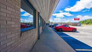 Un hôtel à la façade en briques, doté d’une galerie couverte et d’un parking où sont stationnées plusieurs voitures.