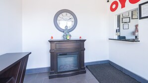 Un espace d’accueil avec une horloge, une cheminée et une enseigne murale portant l’inscription « OYO ».