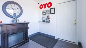 Un couloir avec une horloge, une statue et une porte portant l’inscription « OYO ».