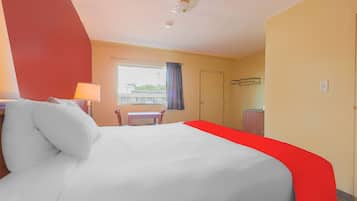 Camera d'albergo con un letto, una scrivania, una sedia, una finestra con tende e un armadio.