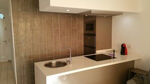 Una cocina moderna con un lavamanos de acero inoxidable, un horno empotrado y un microondas.