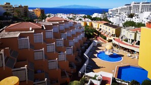A hotel with multiple balconies, a swimming pool, and a view of the sea.