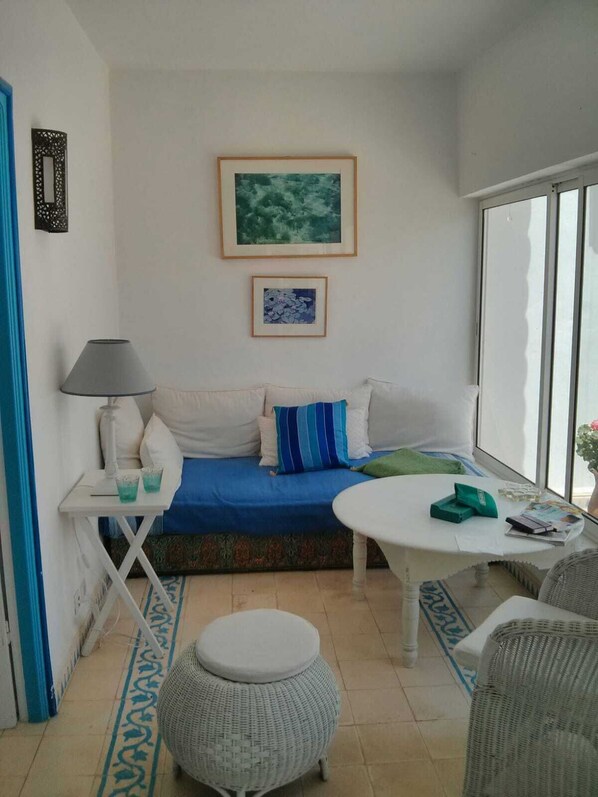 A cozy room with a sofa, a small table, and a wicker ottoman.