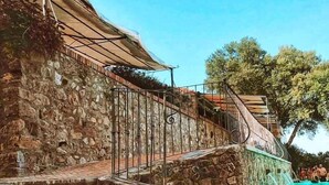 Eine Steintreppe führt zu einem Poolbereich mit Metallgeländer und einer Laterne.