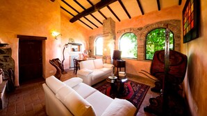Ein gemütliches Wohnzimmer mit Kamin aus Stein, weißen Sofas und Holzboden.