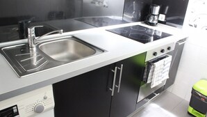 Eine moderne Küche mit Spüle aus Edelstahl, schwarzen Schränken, einem eingebauten Backofen und einer Kaffeemaschine.