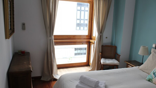 Ein Hotelzimmer mit Bett, Stuhl, Schreibtisch und einem Fenster mit Vorhängen.