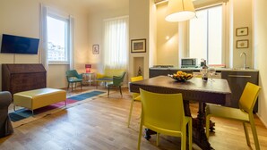 Una sala de estar moderna con comedor, una cocina y un televisor montado en la pared.