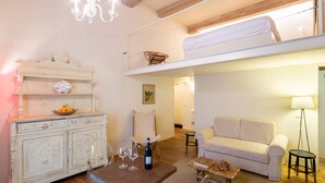 Un salón amplio con techo alto, un sofá blanco, una mesa de comedor con copas de vino y un mueble decorativo.