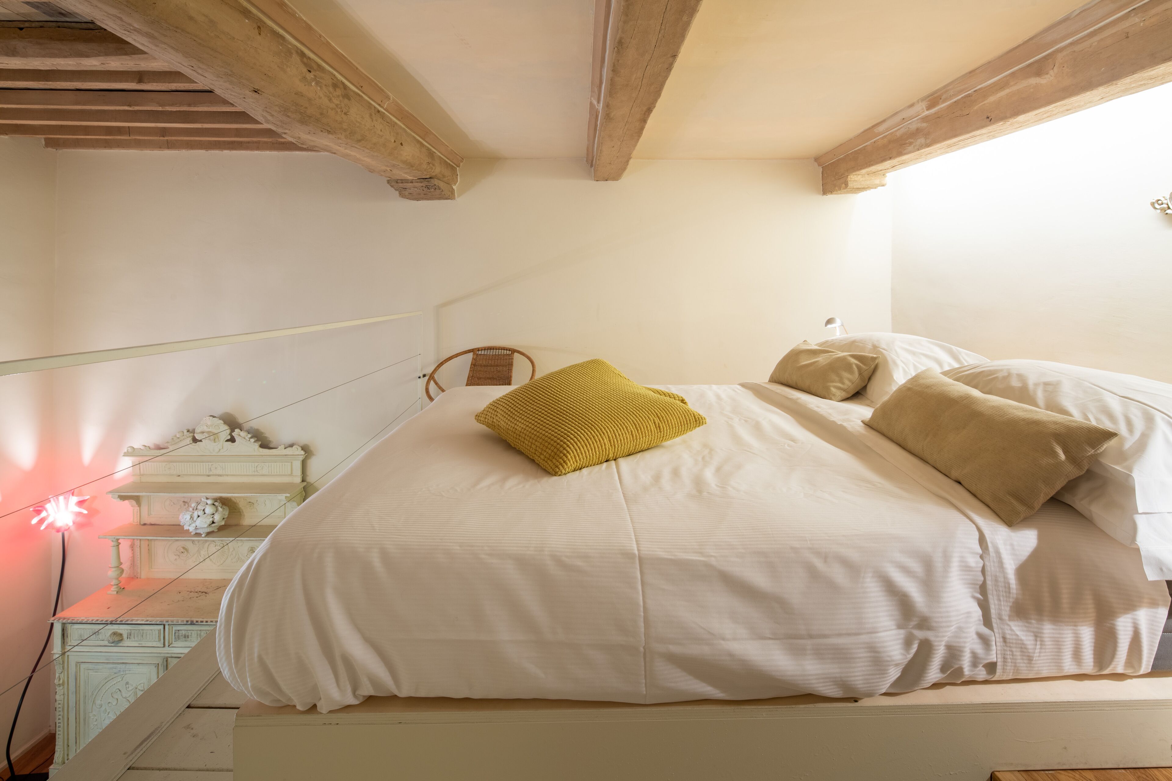 A bedroom with a bed, a wooden headboard, a nightstand, a lamp, and a decorative wall piece.