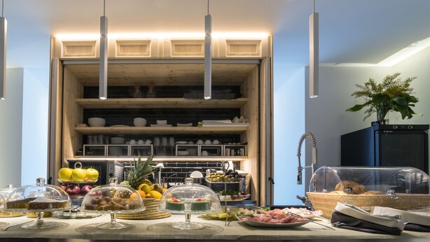 Un buffet de petit-déjeuner proposant une variété d’aliments, avec un coin cuisine en arrière-plan.