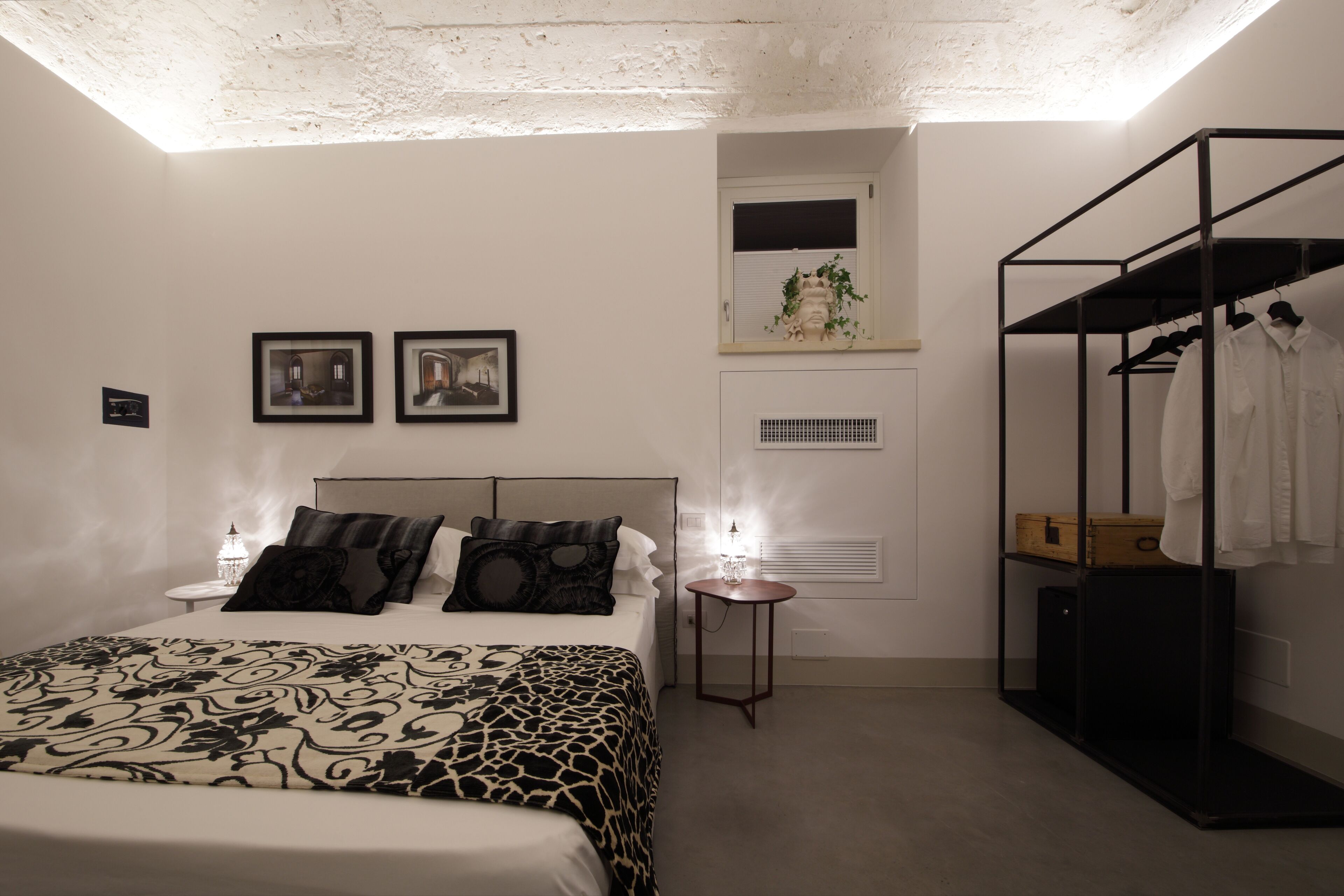 A bedroom with a bed, bedside tables, a wardrobe, and a small window.