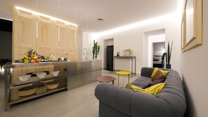 Une cuisine moderne avec des meubles en bois, un îlot central orné de fruits et un canapé gris agrémenté de coussins.