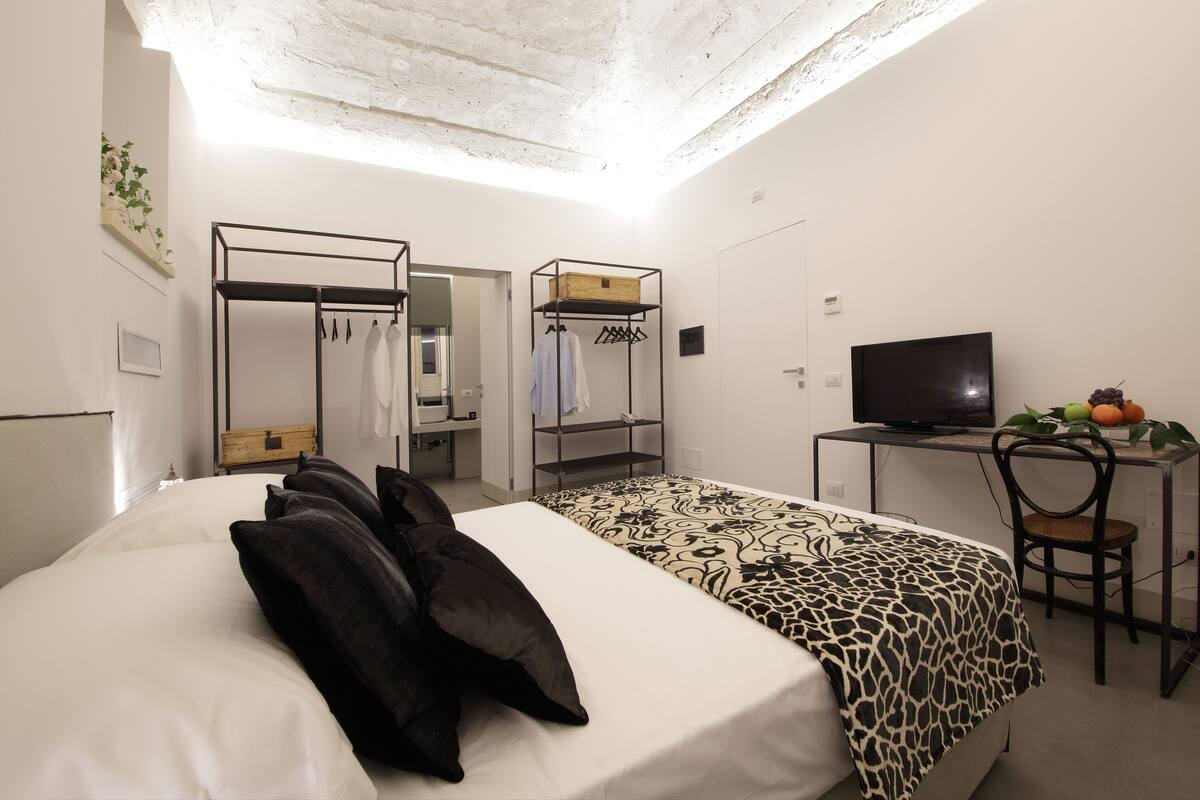 Ein Schlafzimmer mit Bett, Schreibtisch, Fernseher und Kleiderschrank.
