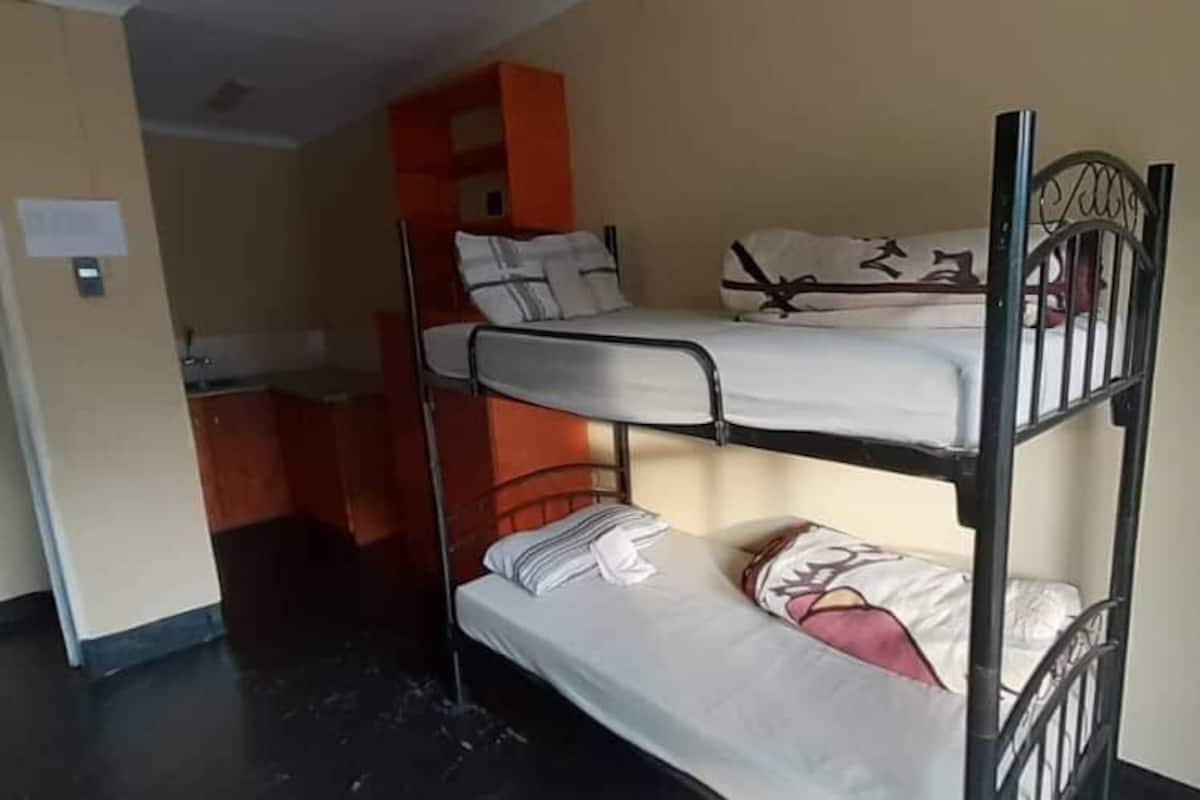 A bunk bed room with a kitchenette area in the background.