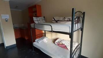 A bunk bed room with a kitchenette area in the background.