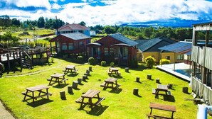 A grassy outdoor area with picnic tables and a wooden deck.
